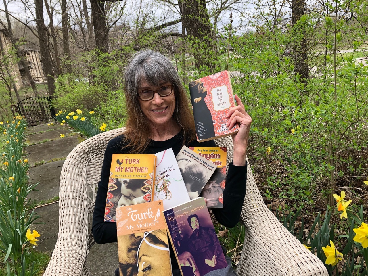 Mary Helen in her front yard with her first novel, The Turk and My Mother, in seven different languages.